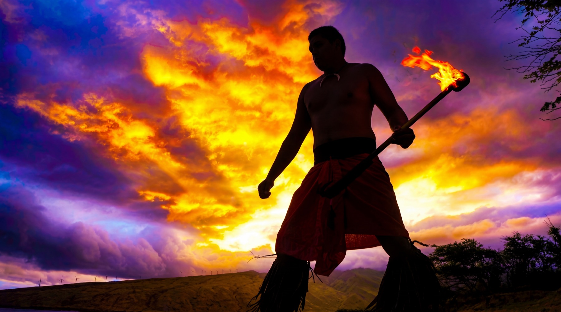 Fire knife dancer silhouetted at sunset on Kauai