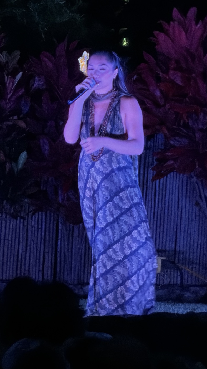 A vocalist sings into a microphone under blue stage lighting
