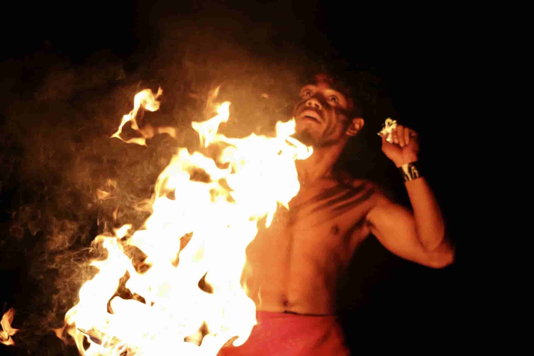 Fire knife performer spinning a wall of flame at night