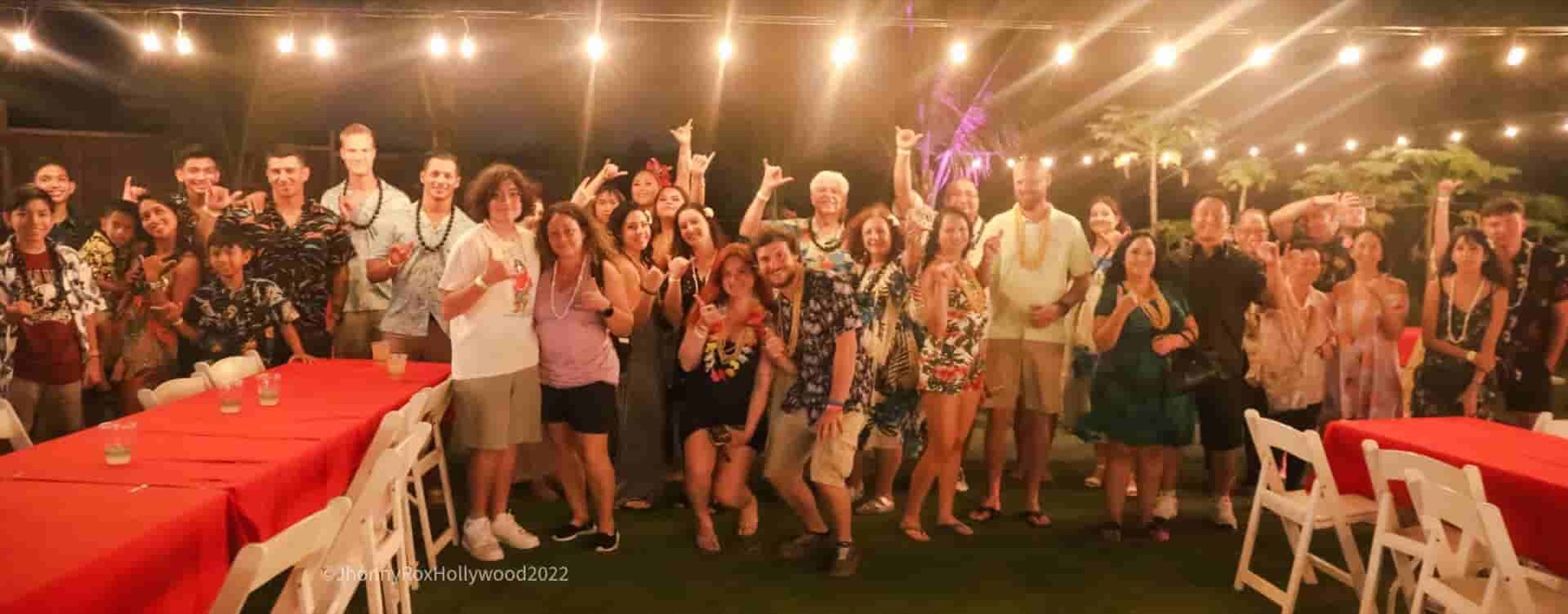 Guests gather for a group photograph beneath string lights
