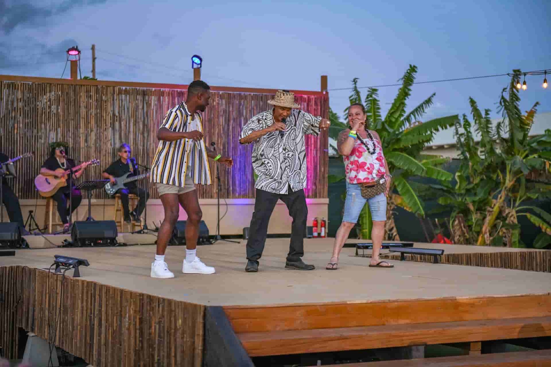 A performer leads two guests in audience participation onstage