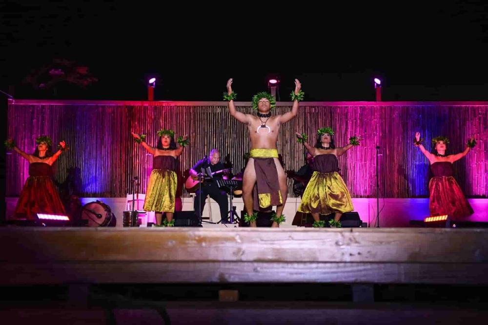 Dancers and a band performing on a stage under pink lights