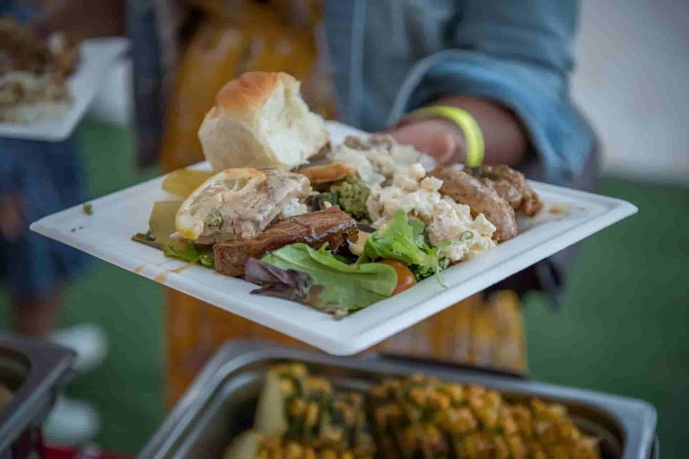 A hand holding a plate of luau food