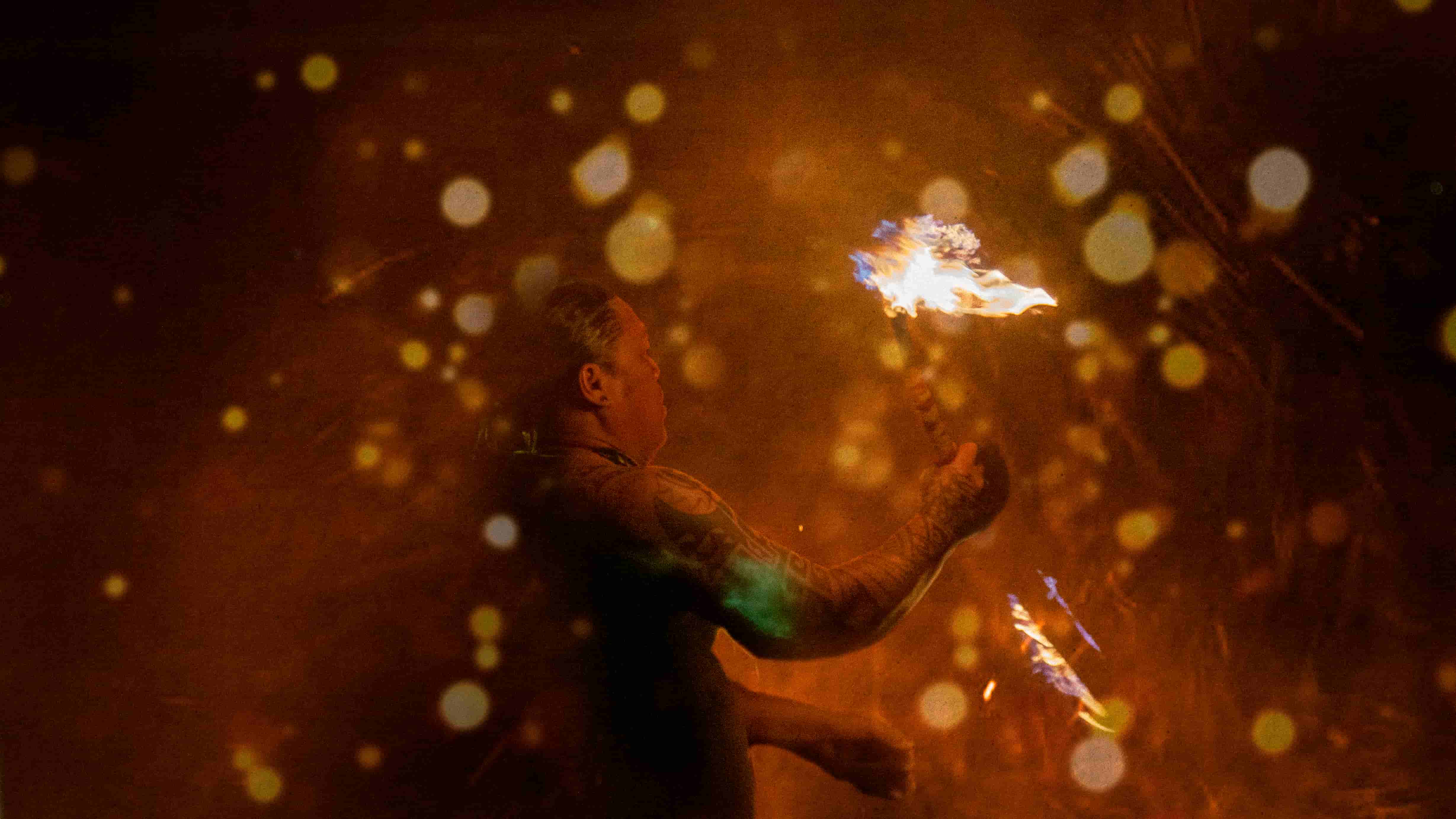 Fire performer with bokeh spark clouds in darkness