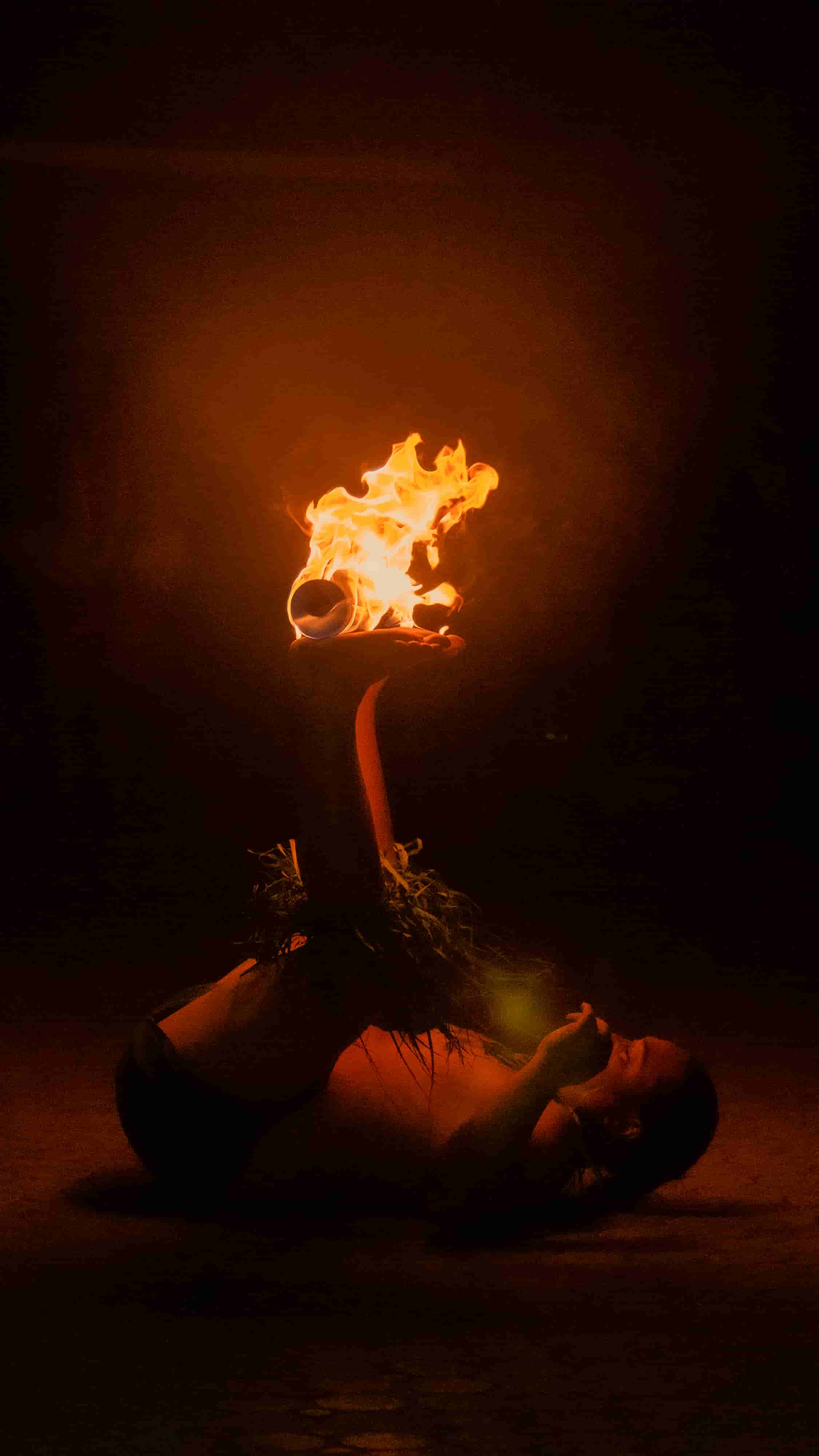 Fire knife performer in dramatic backbend holding flame above