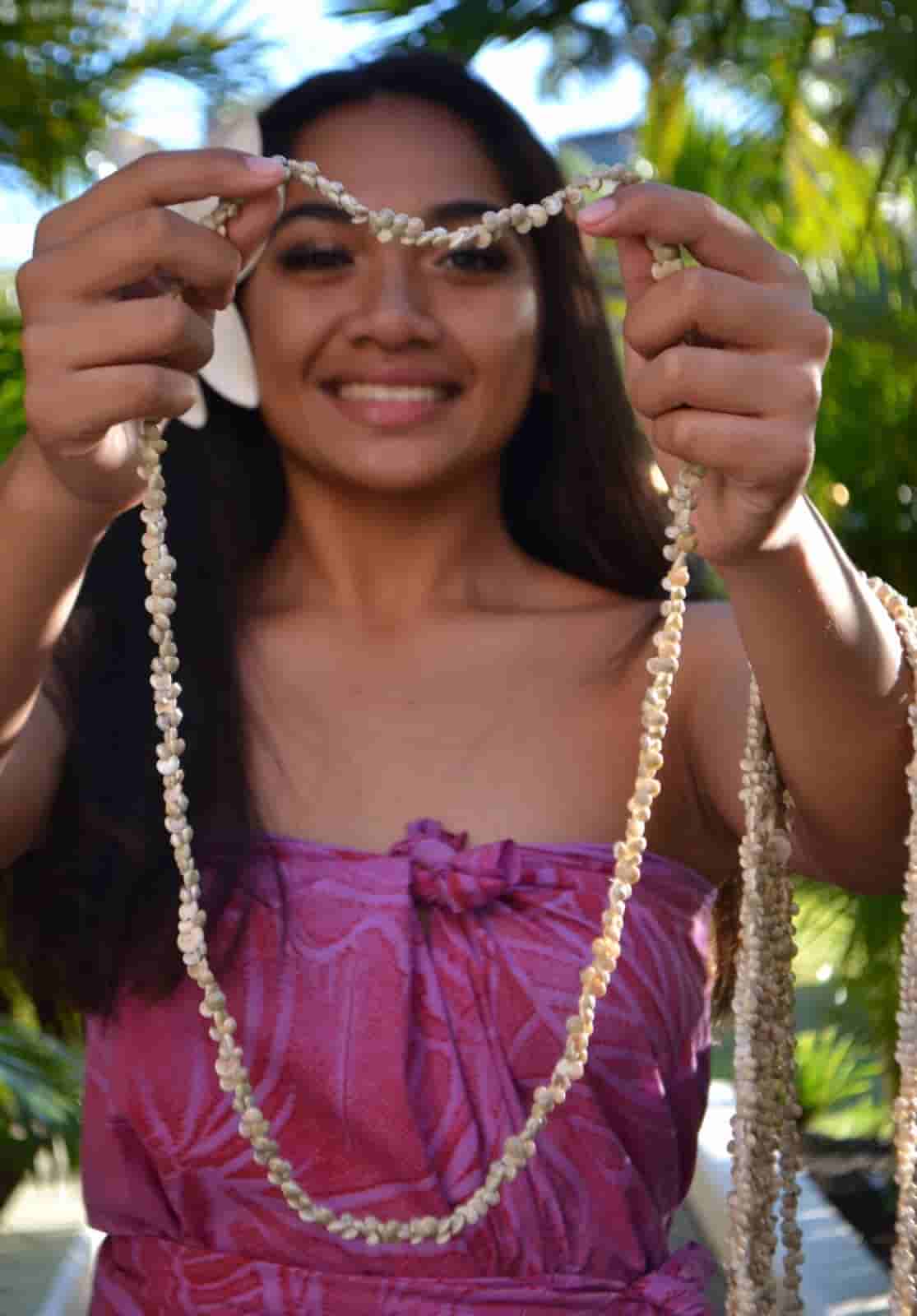 Woman warmly presenting a traditional Hawaiian lei
