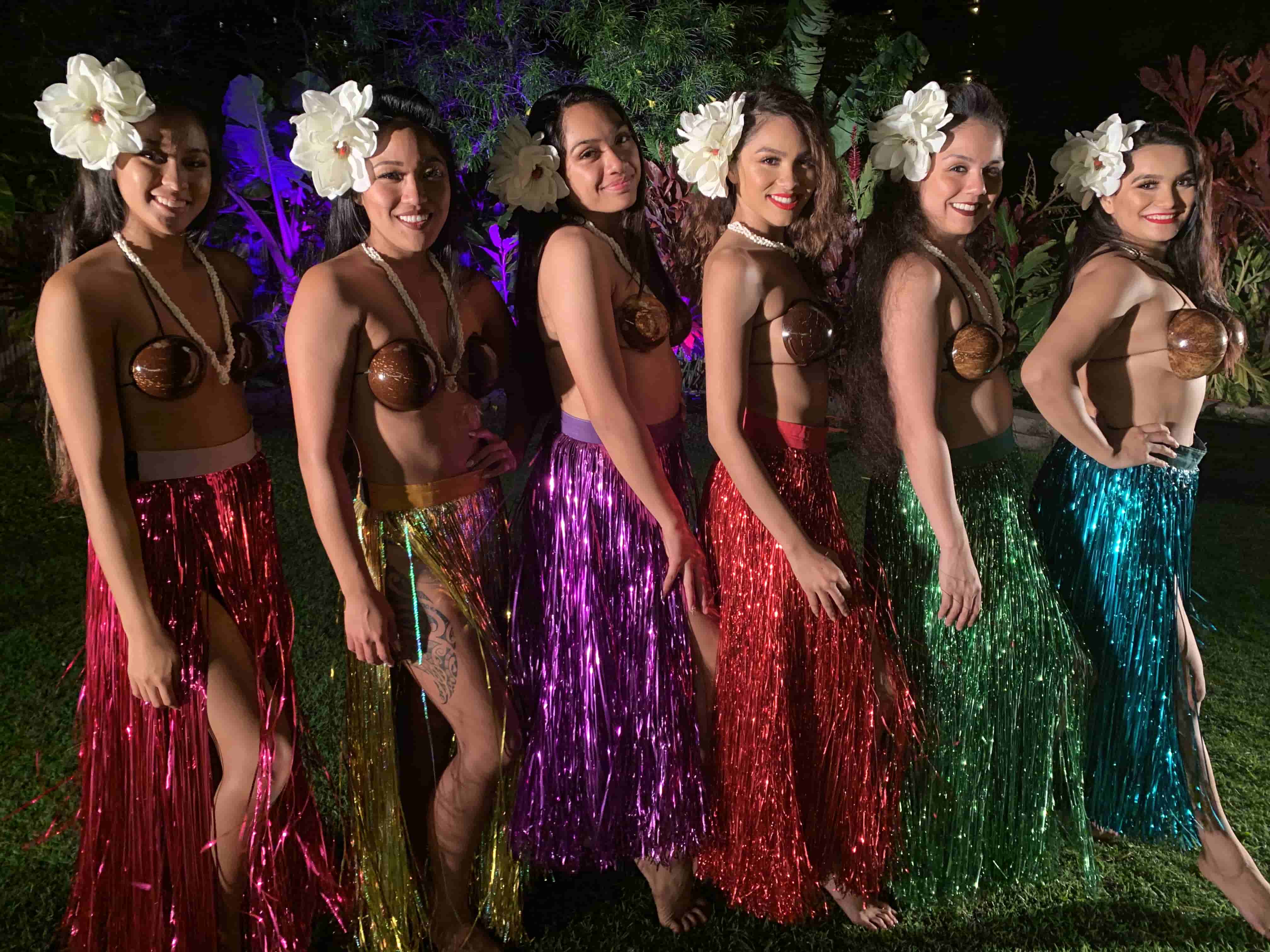 Six Tahitian dancers in vibrant rainbow metallic costumes