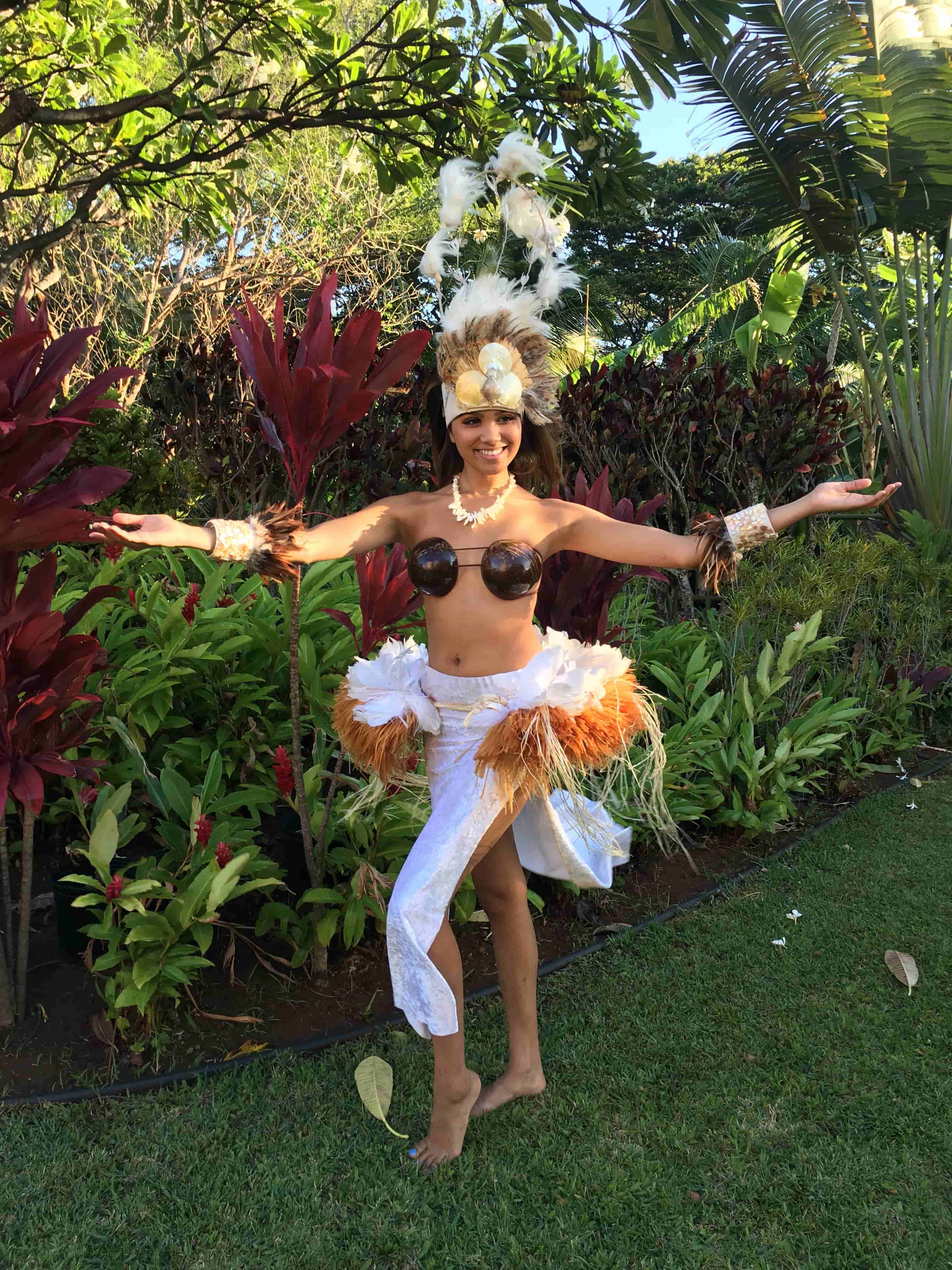 Polynesian dancer in elegant white and feather costume in garden