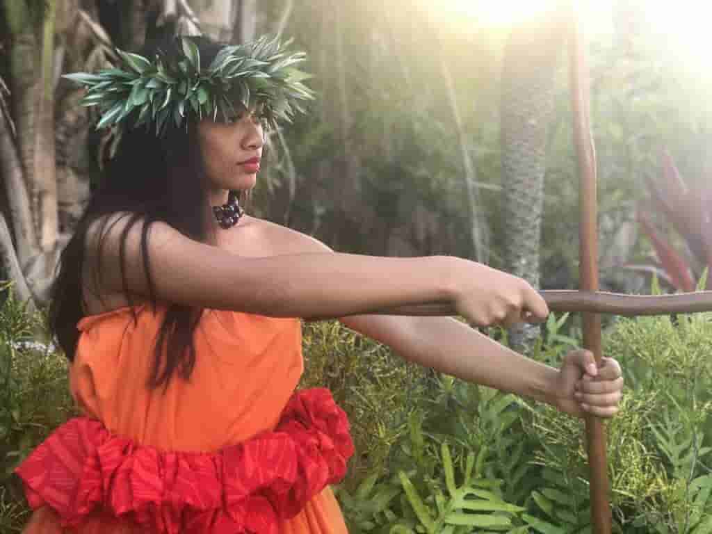 Hula dancer with traditional stick in sunlit rainforest