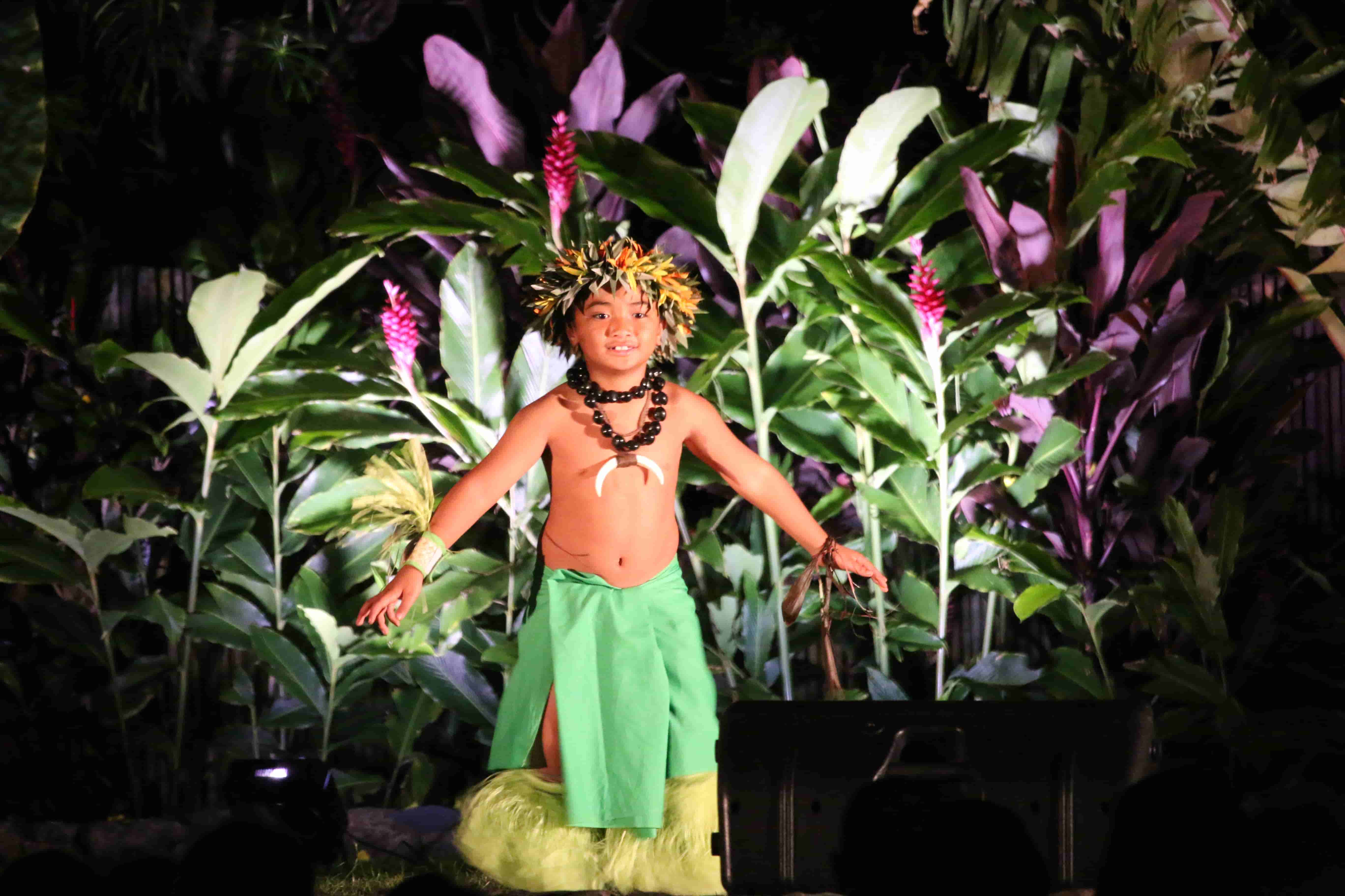Young boy performing traditional hula on a lit stage