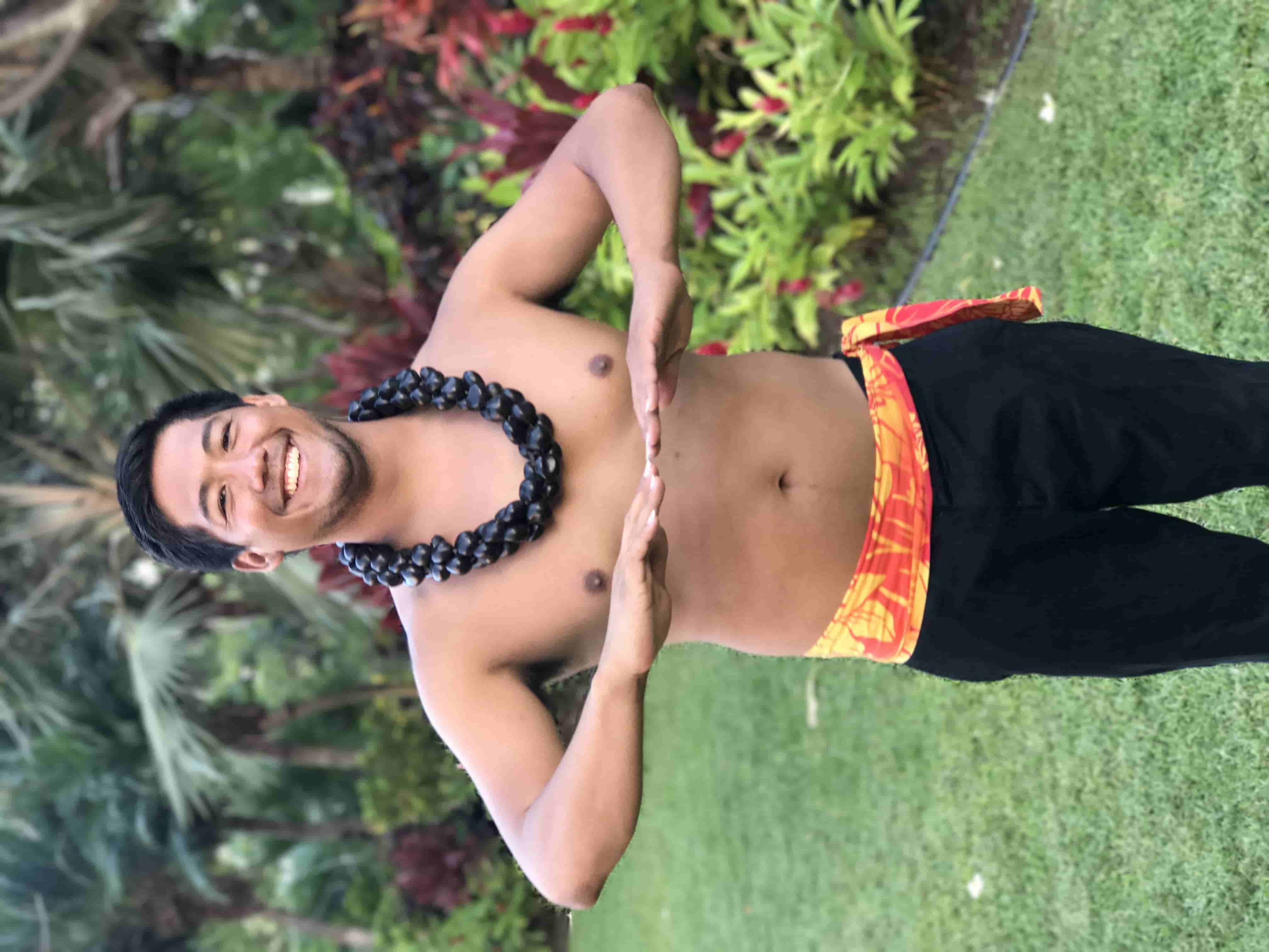 Male hula dancer in traditional costume and black kukui lei