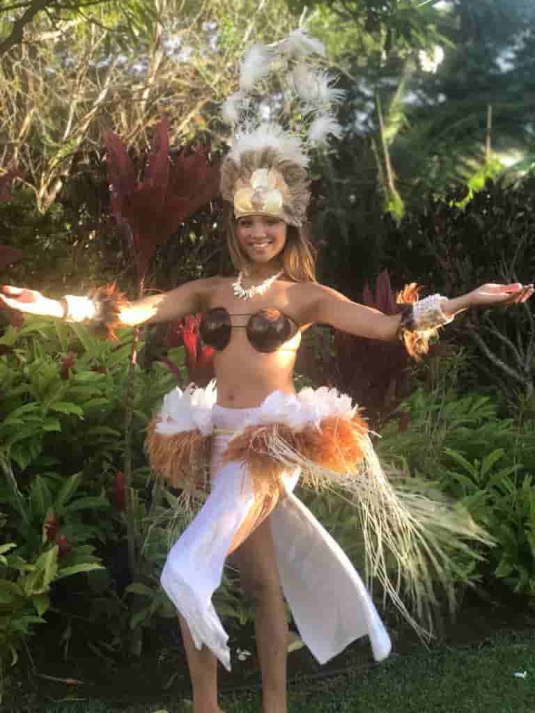 Polynesian dancer in white feather headdress and costume in lush garden