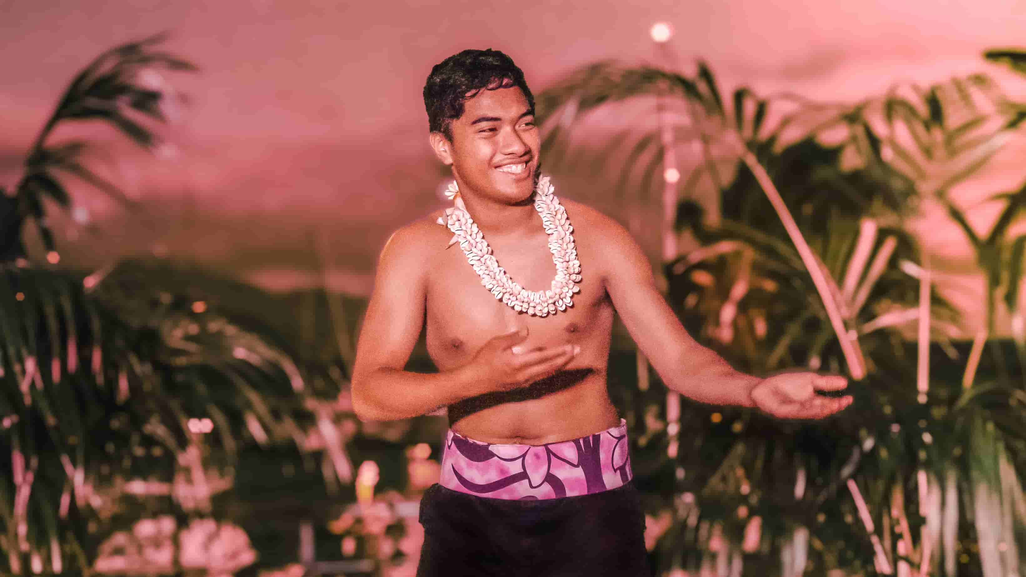 Smiling young male dancer with shell lei in traditional dress