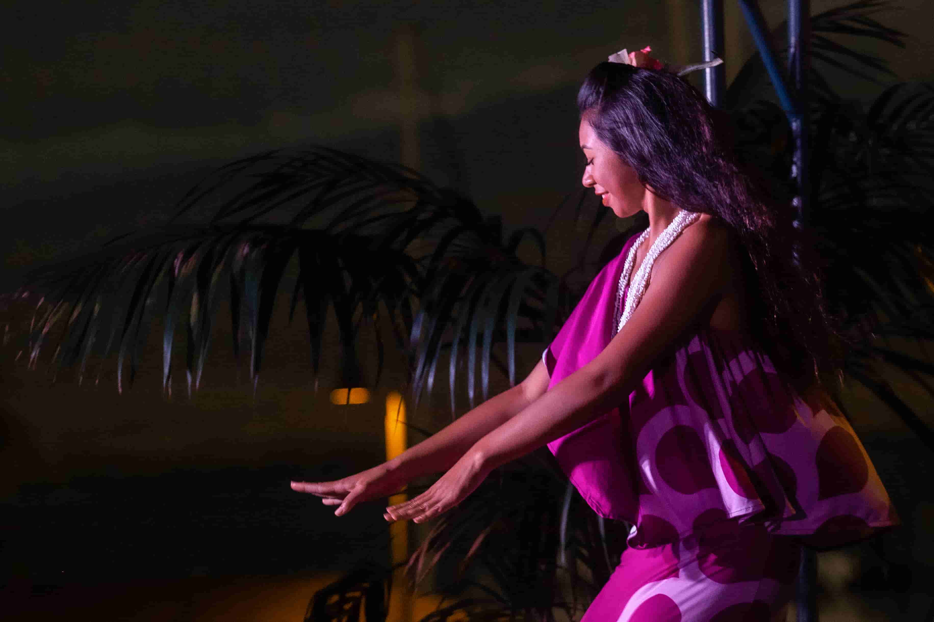Hula dancer in flowing magenta dress in profile