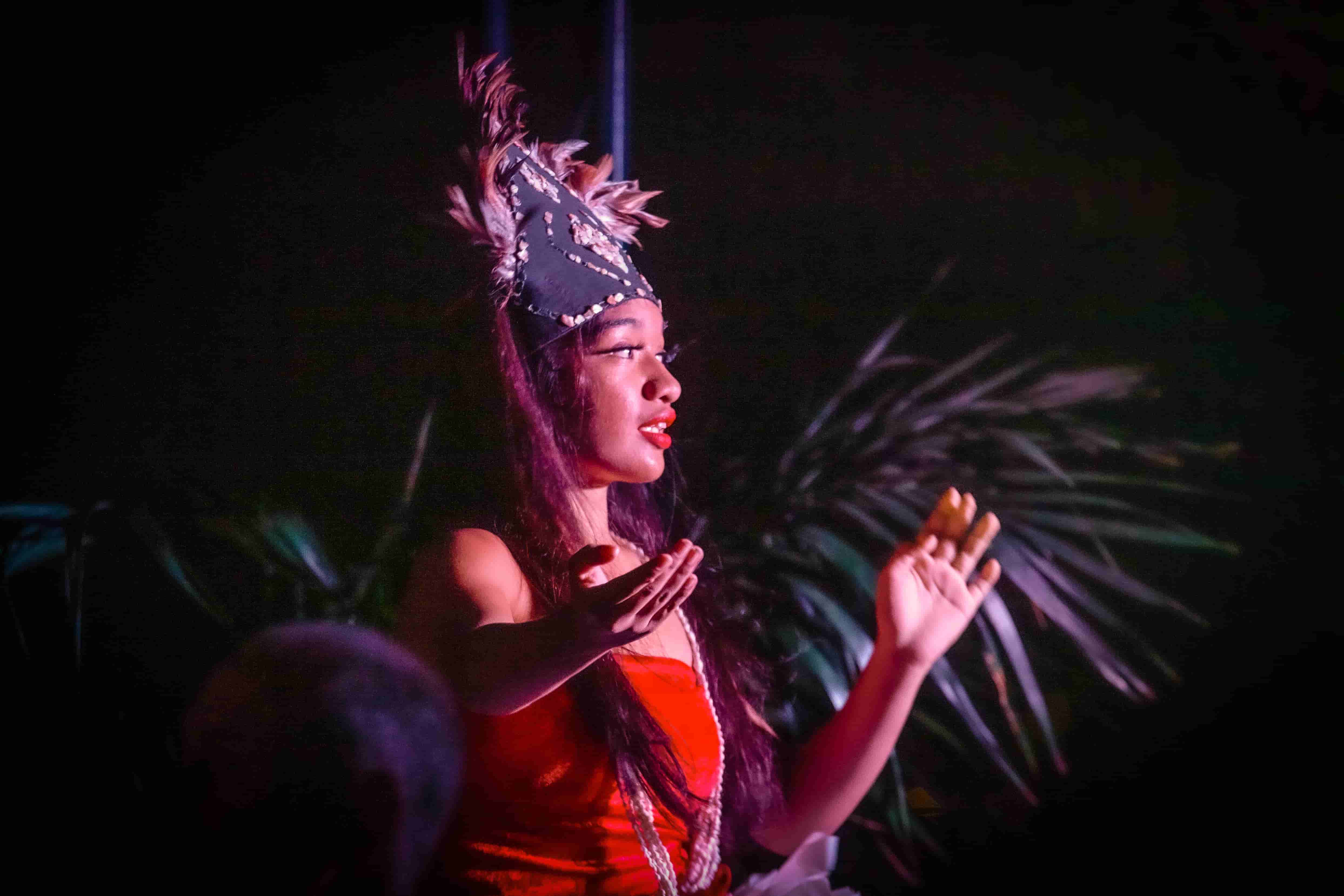 Polynesian dancer with feathered crown, dramatic night lighting