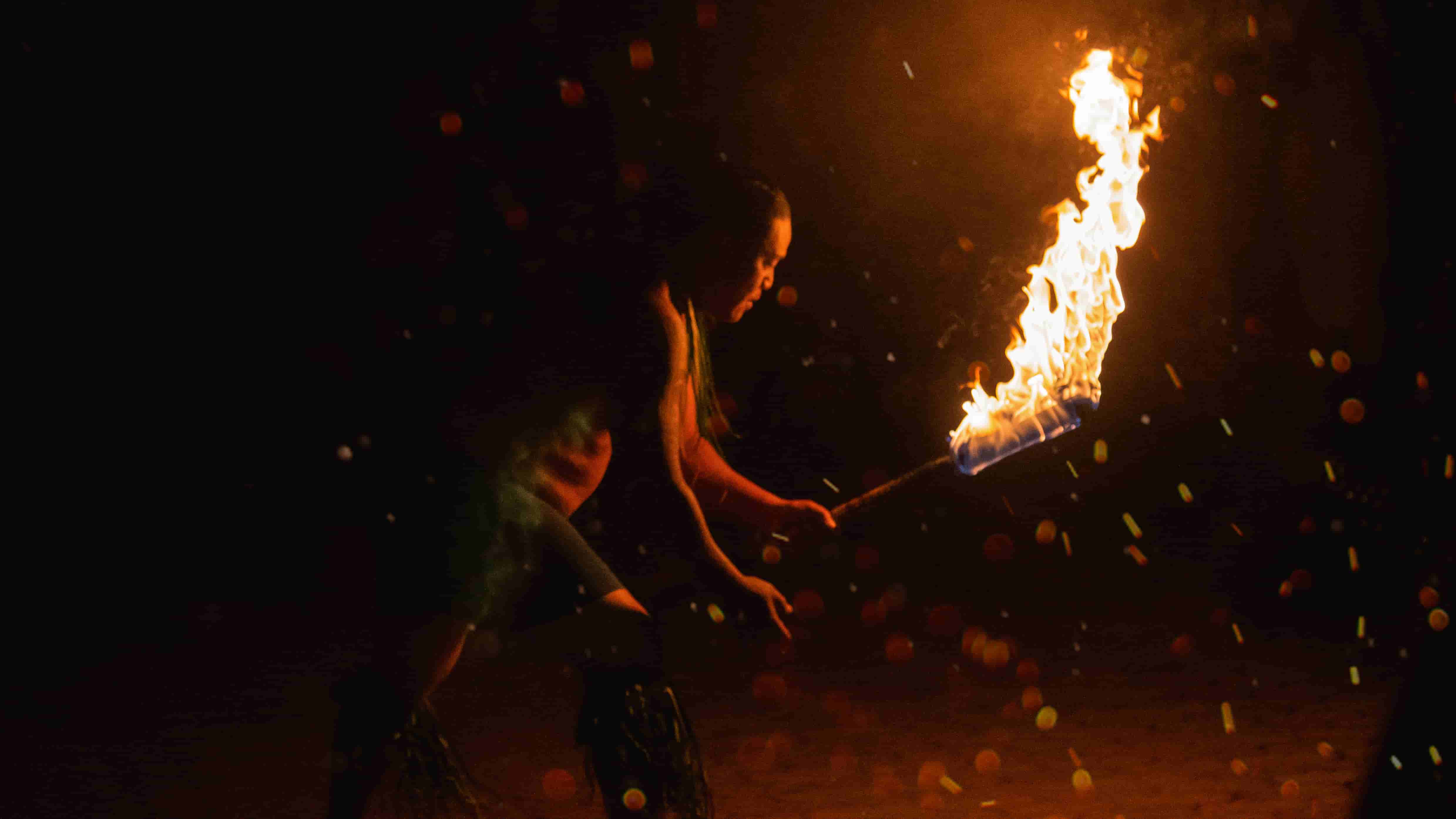 Fire torch performer with dramatic flames at night